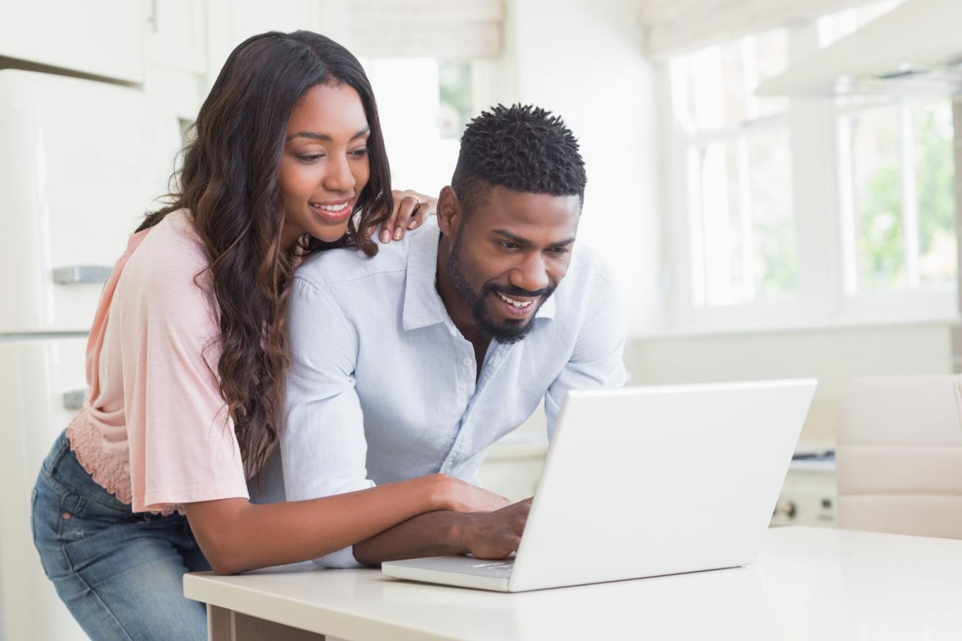 A couple in a kitchen looking at a laptop