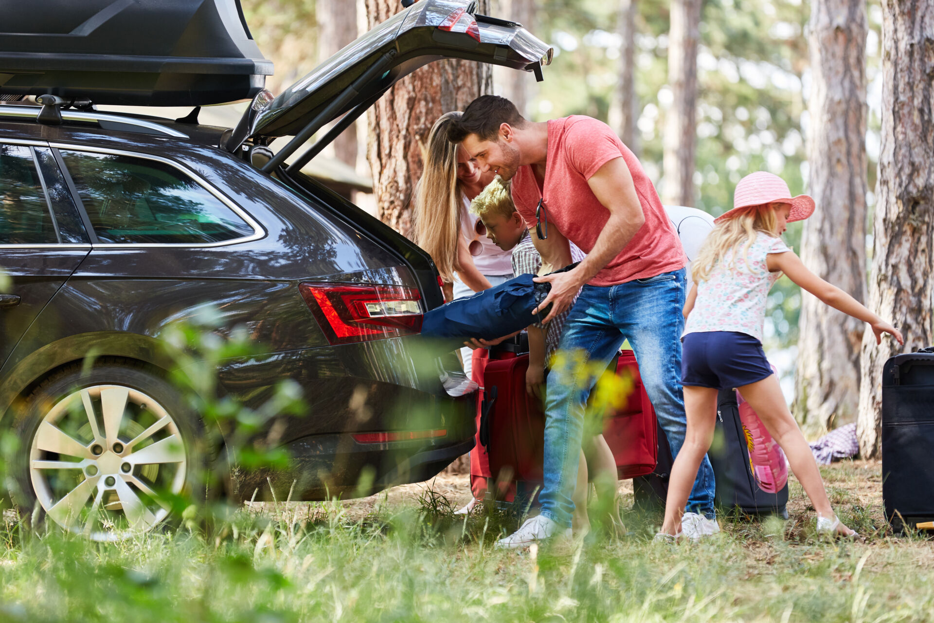 A family unpacks their car at a campsite.