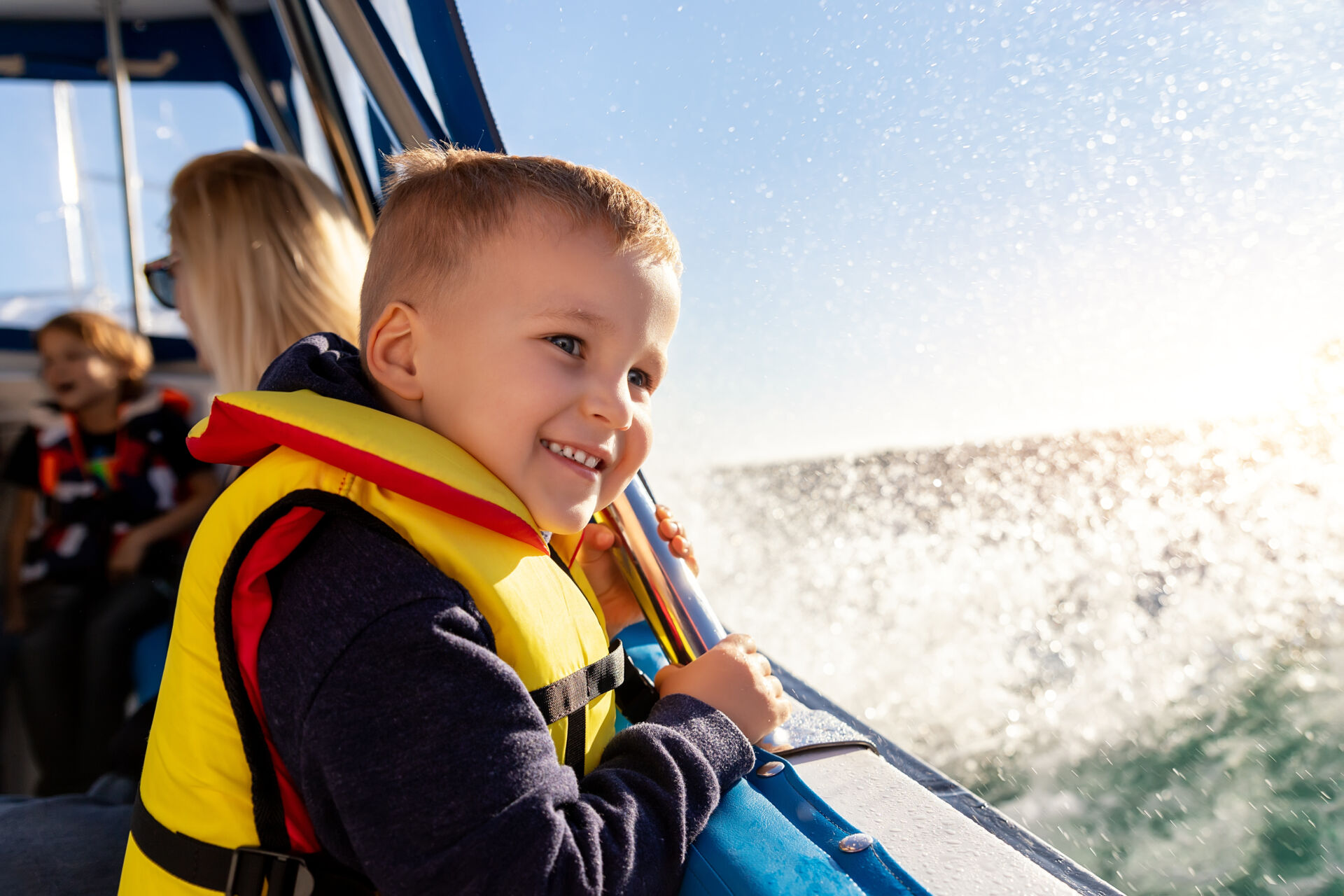 A little kid is smiling as he and his family have fun on their new boat.