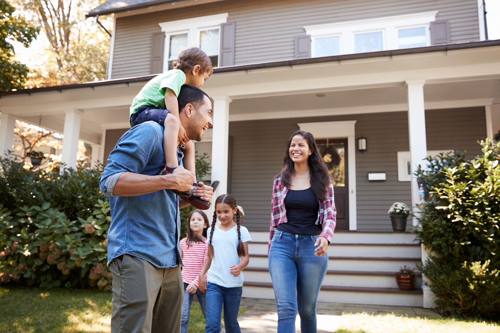 A young couple with three children walk down the sidewalk of their new home.